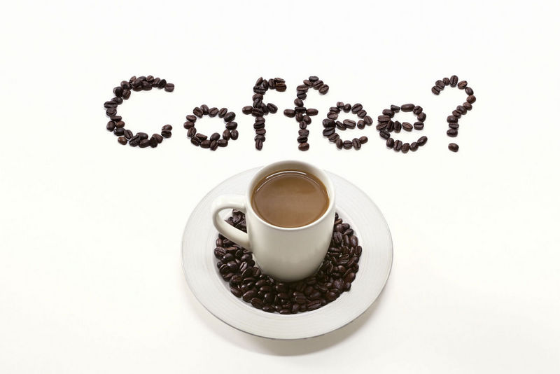 Cup of coffee on white background with coffee spelled out in coffee beans National Coffee Day